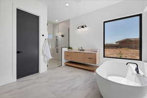 Bathroom featuring a freestanding bath, a stall shower, vanity, and recessed lighting