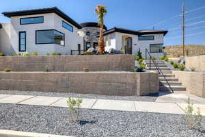 Modern home featuring concrete block siding, stairs, and a metal roof