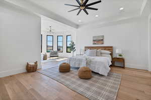 Bedroom featuring recessed lighting, a tray ceiling, light wood finished floors, a chandelier, and a ceiling fan