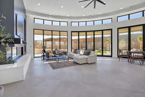 Living area with recessed lighting, a towering ceiling, healthy amount of natural light, and ceiling fan