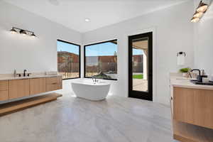 Bathroom featuring two vanities, a freestanding bath, and recessed lighting