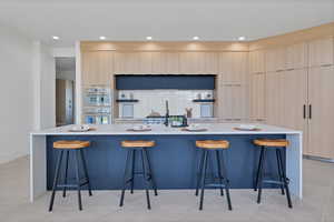 Kitchen featuring a breakfast bar, light brown cabinetry, a spacious island, light stone countertops, and recessed lighting