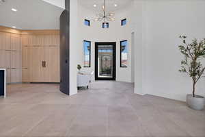 Entrance foyer featuring a towering ceiling, light tile patterned floors, recessed lighting, and a chandelier