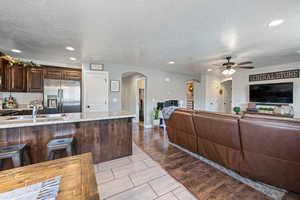 Kitchen with dark brown cabinetry, arched walkways, stainless steel appliances, light wood finished floors, and recessed lighting
