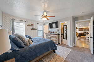 Bedroom with a textured ceiling, light carpet, and ceiling fan
