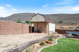 View of shed with a trampoline, a fenced backyard, and a mountain view