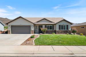 Ranch-style house with stone siding, stucco siding, concrete driveway, and a front lawn