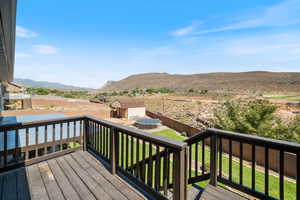 Deck with a mountain view, an outbuilding, and a fenced backyard