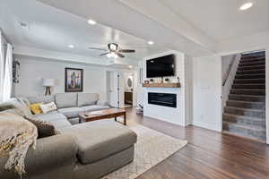 Living area with recessed lighting, wood finished floors, a ceiling fan, a fireplace, and stairway