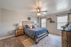 Carpeted bedroom with a ceiling fan and a textured ceiling
