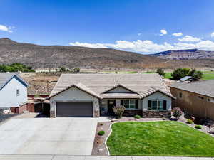 Ranch-style house with stone siding, driveway, a mountain view, and an attached garage
