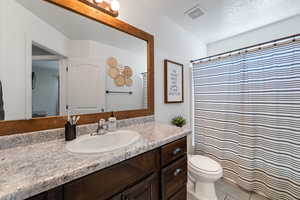 Full bath featuring a textured ceiling, vanity, and a shower with shower curtain