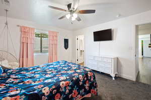 Carpeted bedroom with ceiling fan and a textured ceiling