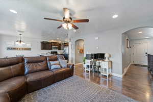 Living area featuring arched walkways, a textured ceiling, recessed lighting, dark wood finished floors, and ceiling fan
