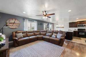 Living area with a textured ceiling, hardwood / wood-style flooring, a chandelier, a ceiling fan, and recessed lighting