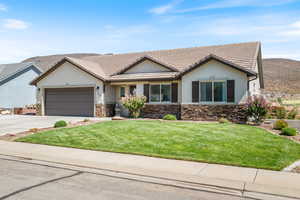 Ranch-style home featuring stone siding, a front yard, driveway, and stucco siding