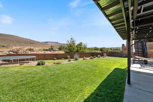 Fenced backyard featuring a trampoline, stairway, and a mountain view