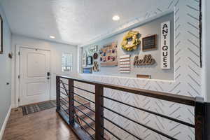 Hallway with a textured ceiling, dark wood-style floors, and recessed lighting