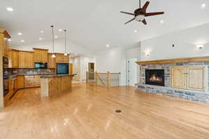 Great room with wood floors, gas stone fireplace, and high vaulted ceiling