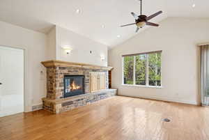 Great room with wood floors, gas stone fireplace, and high vaulted ceiling