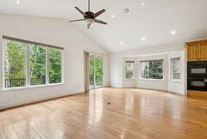 Great room with wood floors, gas stone fireplace, and high vaulted ceiling