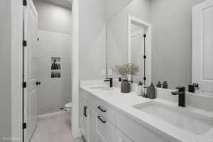 Basement Bathroom featuring a shower stall and double vanity