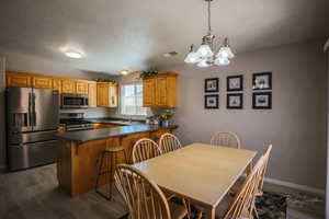 Kitchen with dark countertops, appliances with stainless steel finishes, a peninsula, a textured ceiling, and a chandelier