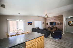 Kitchen featuring wooden walls, light brown cabinetry, an accent wall, wood tiled floors, and dark countertops