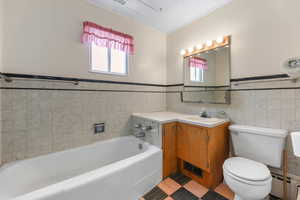 Bathroom with tile walls, a garden tub, vanity, wainscoting, and baseboard heating