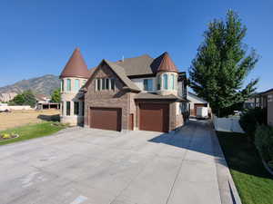 View of front of property featuring driveway, a standing seam roof, brick siding, a metal roof, and an attached garage