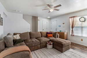 Living room with wood finished floors, a textured ceiling, and ceiling fan
