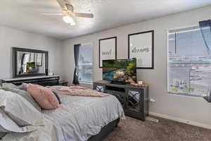 Carpeted bedroom with a textured ceiling and a ceiling fan