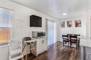 Kitchen with stainless steel microwave, dark wood-style floors, light countertops, and a textured ceiling
