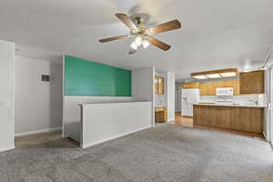 Unfurnished living room with light carpet, a textured ceiling, and a ceiling fan