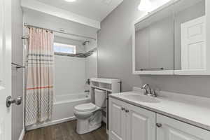 Bathroom featuring shower / bath combination with curtain, dark wood-type flooring, vanity, and a textured ceiling