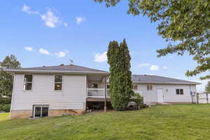 Back of house with a lawn, a deck, and roof with shingles