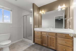 Full bathroom with vanity, a stall shower, light tile patterned floors, and a ceiling fan