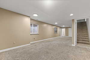 Below grade area featuring light colored carpet, stairway, and recessed lighting