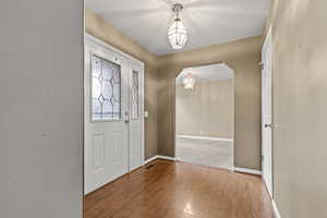 Foyer entrance featuring wood finished floors, arched walkways, and a chandelier