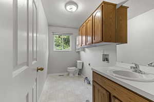 Bathroom with light flooring, vanity, and a textured ceiling