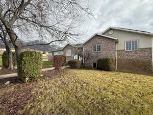 View of side of property with brick siding, a lawn, and stucco siding