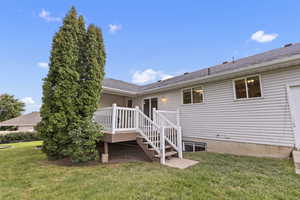Back of property featuring a wooden deck, a lawn, and stairs