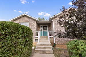Property entrance featuring brick siding and covered porch