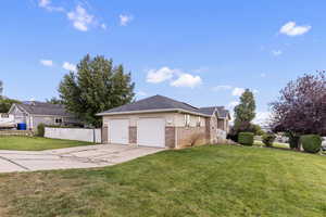 View of property exterior with driveway, brick siding, an attached garage, and solar panels