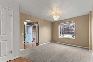 Unfurnished room with arched walkways, a chandelier, and light wood-style floors