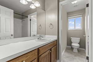 Bathroom featuring vanity, light tile patterned floors, and a shower