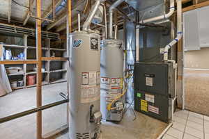 Utility room with gas water heater, water heater, and heating unit