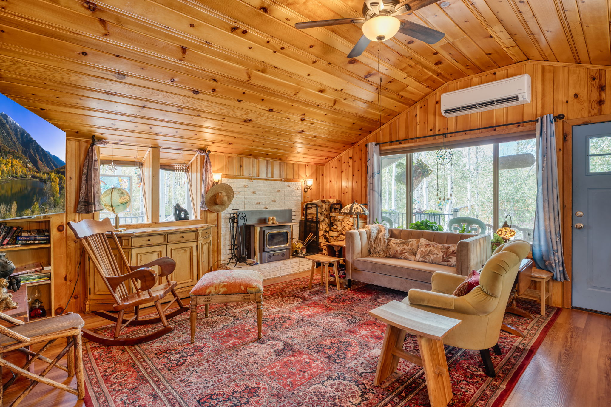 Living area with wood finished floors, healthy amount of natural light, lofted ceiling, wood walls, and wooden ceiling