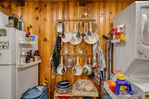 Detailed view of wooden walls, stacked washer and clothes dryer, and freestanding refrigerator