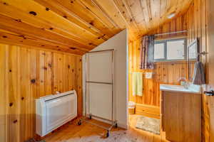 Washroom with wood-type flooring, wooden walls, wooden ceiling, and heating unit